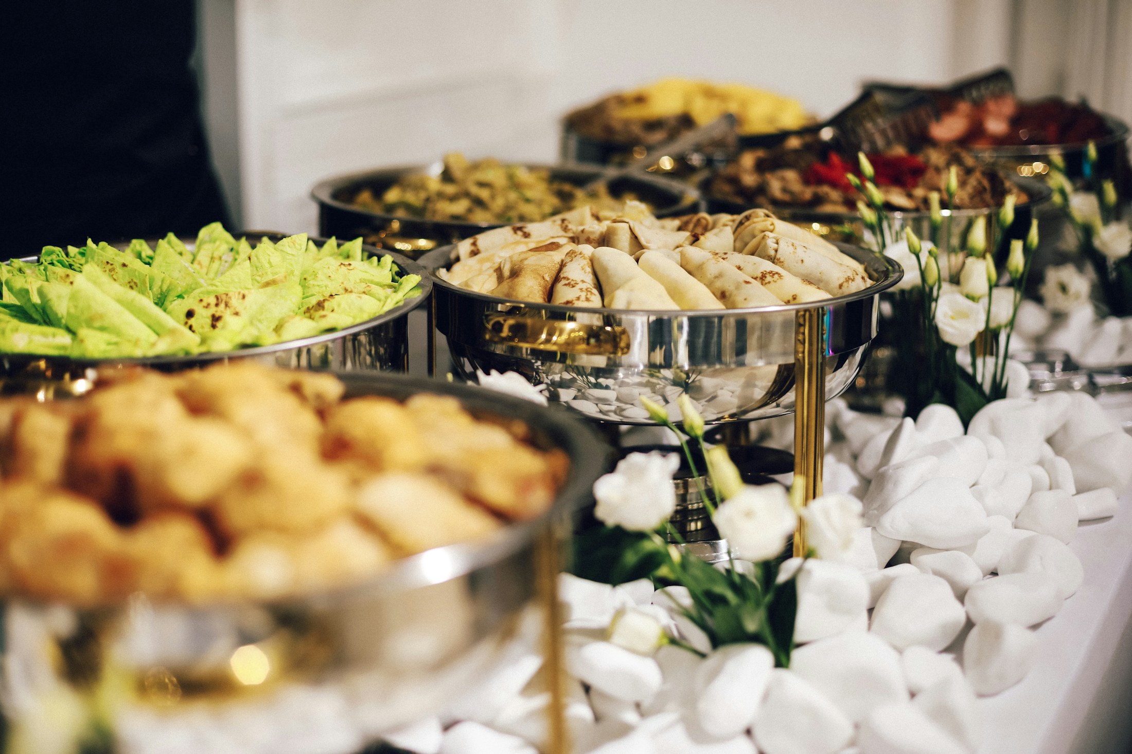 Buffet table with silver chafing dishes filled with prepared catering food